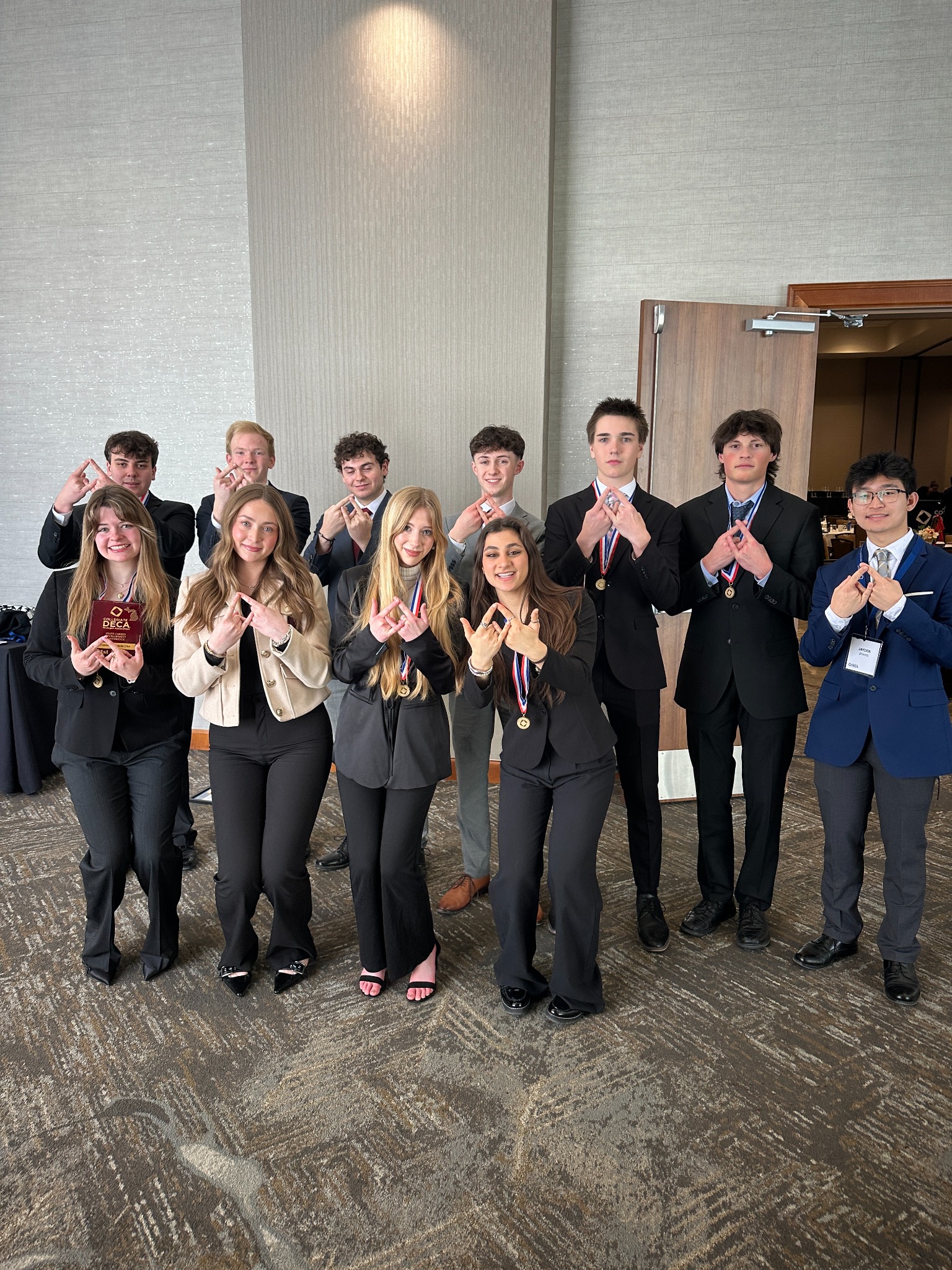 Michigan Collegiate DECA members celebrating with medals and an award